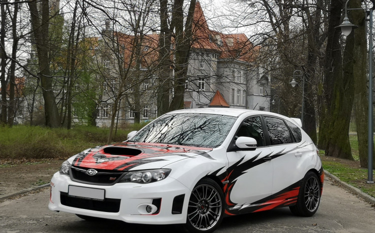 subaru impreza w ciekawym malowaniu na tle drzew oraz budynku