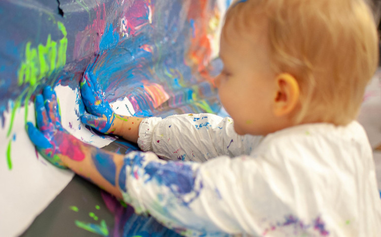 dziecko maluje rączkami umoczonymi w farbie