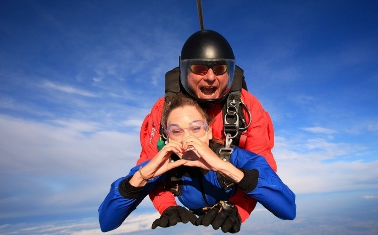 kobieta pokazuje serduszko skacząc ze spadochronem
