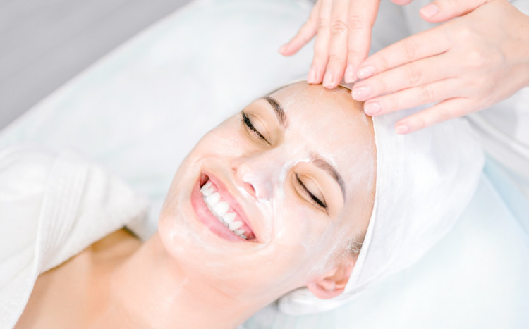 uśmiechnięta kobieta z maską na twarzy podczas masażu głowy